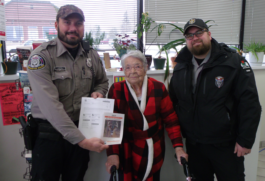 Florence Teeters poses with DNR Wardens after buying her first gun deer license.